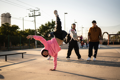 Young woman breakdancing during street party with his friends