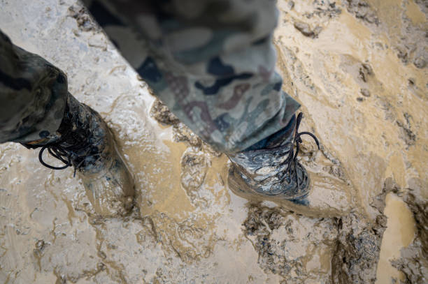 close-up for a man's legs in military camouflage with a trekking wellington shoes dirty in mud - mud dirt road road dirt imagens e fotografias de stock