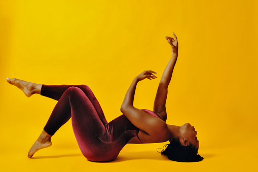 Contemporary dancer in energetic pose on the studio floor.  African American Woman.
