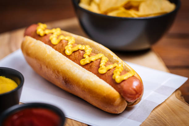 Fresh Hot Dog on Wooden Background Hot Dog sausage and bun with ketchup and mustard sauce and lettuce and potato chips on Wooden Background hot dog stock pictures, royalty-free photos & images