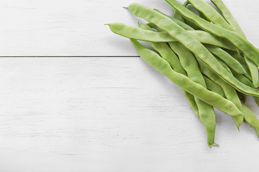 Raw green beans on wooden