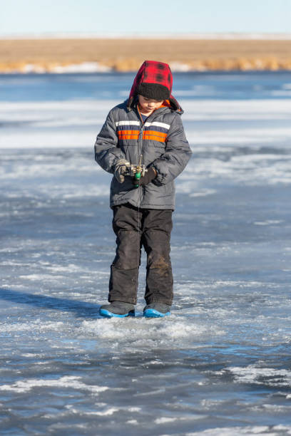 istock Young Boy Standing While Ice Fishing in Winter 1457132126