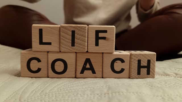 Woman composes the text life coach from wooden blocks
