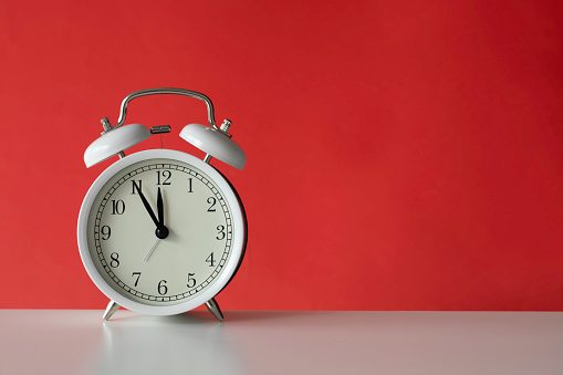 Retro style alarm clock on red background.