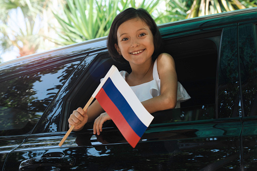 Girl holding Russian Flag in the car.