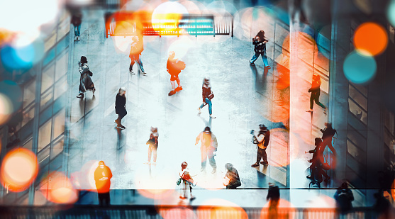 Modern city life with an abstract style: unrecognizable people walking in a busy space at rush hour with street lights. High contrast with blurred motion, bokeh and multiple exposure effect.