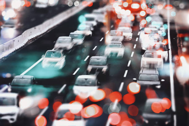 Abstract composition of highway traffic jam with city lights and a large group of cars waiting in line, with blurred city lights. Rush hour, environmental issues, modern lifestyle.