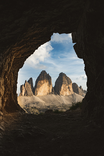 Stunning view of the Three Peaks of Lavaredo, (Tre cime di Lavaredo) during a beautiful sunset framed by a cave. The Three Peaks of Lavaredo are the undisputed symbol of the Dolomites, Italy.