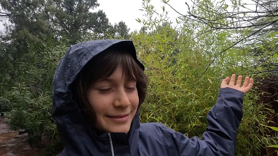 A ten year old girl in he rain jacket enjoying the rain fall