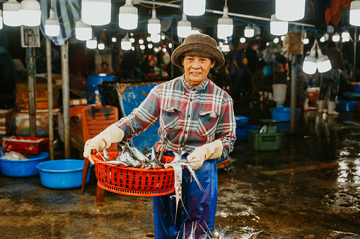 woman with basket full of fish selling fish at the market in Hoi An, Vietnam