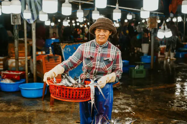 Photo of woman with fish basket selling fish at the market in Hoi An, Vietnam