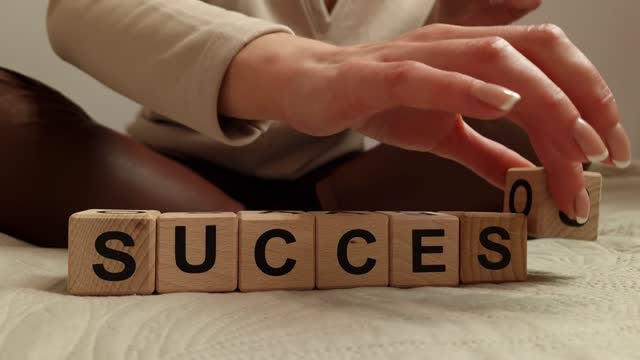 Woman composes the word success from wooden blocks