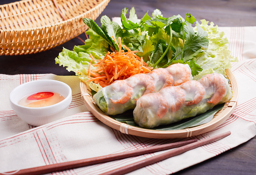 Fresh Vietnamese salad rolls with prawns on a plate decorated with fresh herbs. Top view High-quality photo