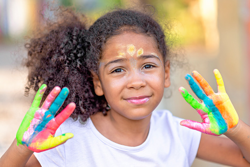 beautiful happy girl with painted hands, artistic, educational, fun concepts, colorful background