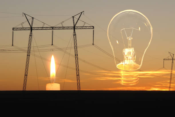 istock Burning candle, unlit light bulb and high voltage power lines. 1457145771