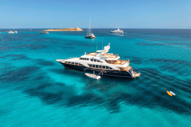 vista aerea dello yacht di lusso sul mare blu in una giornata di sole in estate. sardegna, italia. vista aerea di motoscafi, yacht, laguna marina, riva, acqua trasparente, cielo. vista dall'alto dal drone. paesaggio marino tropicale - yacht foto e immagini stock