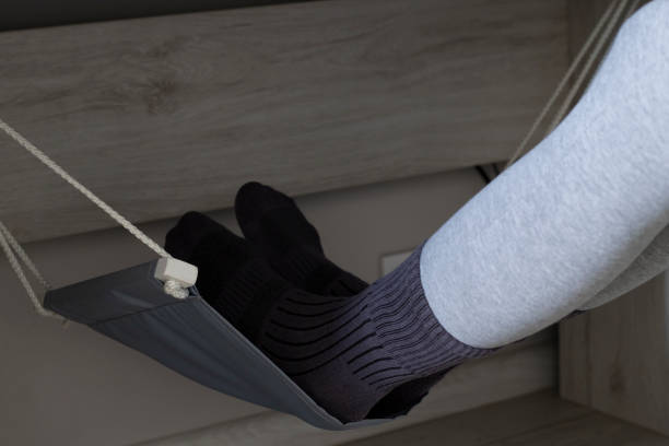 Woman uses a footstool while working on her computer at home, close-up. Hammock for blood drainage from feet