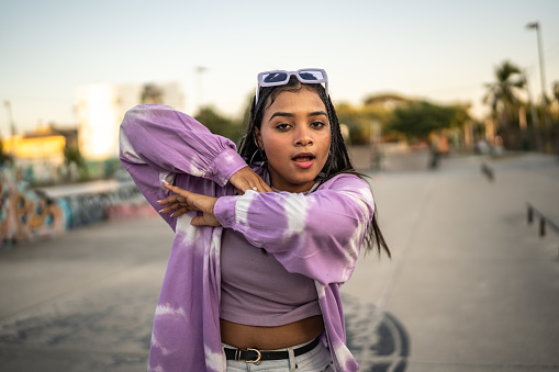 Portrait of young woman dancing hip hop at skateboard park