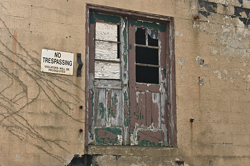 Detail of an abandoned factory exterior in Connecticut, with No Trespassing sign