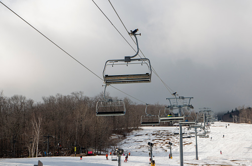 Close-up shot of male legs on ski board and woman standing on skies in background while resting on ski slope