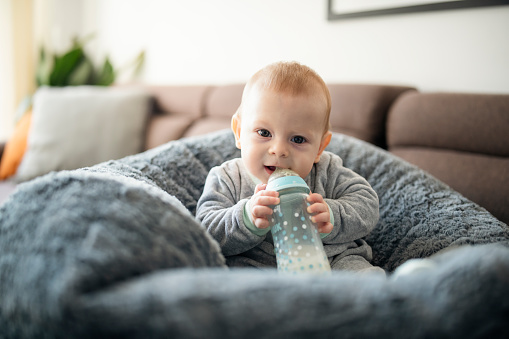 Shot of cute baby boy sitting in a bean bag with a bottle of milk.