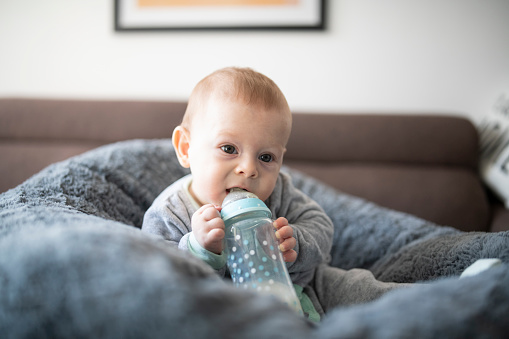 Shot of cute baby boy sitting in a bean bag with a bottle of milk.