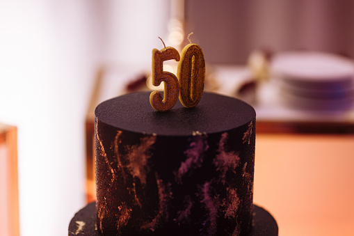 Chocolate birthday cake with golden details, fifty years Anniversary , 50 years candle. Candy bar, buffet sweet bar. Festive party.
