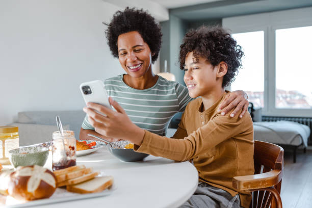 istock African-American boy using phone while having breakfast with his mother 1457154063