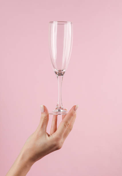 istock Empty champagne glass in a female hand on a pink background 1457154081
