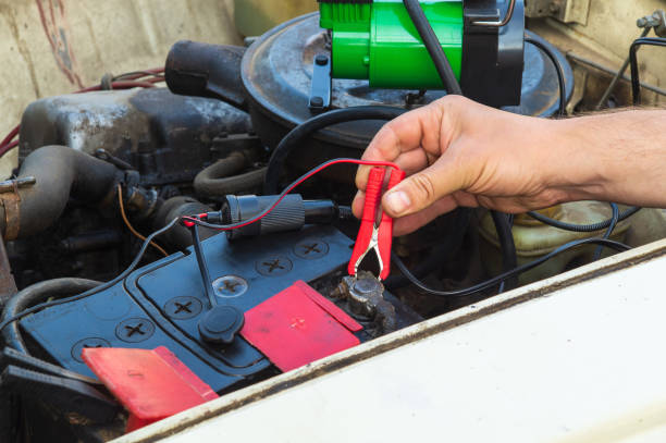 istock Close up of driver hand charging old car battery using electricity through jumper cables. Repair of an old car 1457154895