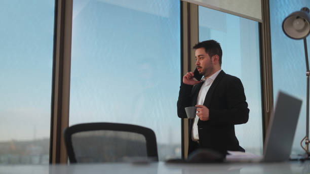 istock Young businessman working at office and talking on phone 1457155942