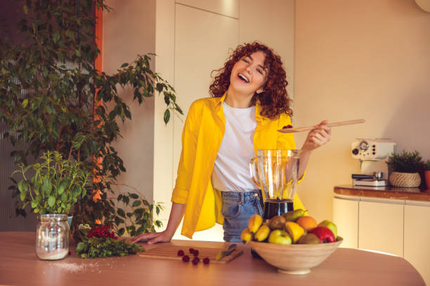 istock Young cute girl in yellow jacket making smoothie in the kitchen 1457156367