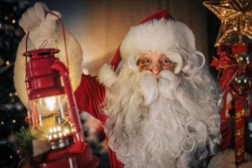 Portrait of Santa Claus holding a lantern and scepter at home.
