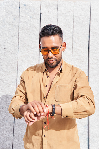 portrait of a latin man with sunglasses looking at the clock
