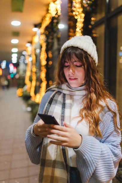 istock Smiling young woman using her phone outdoors at night 1457168862