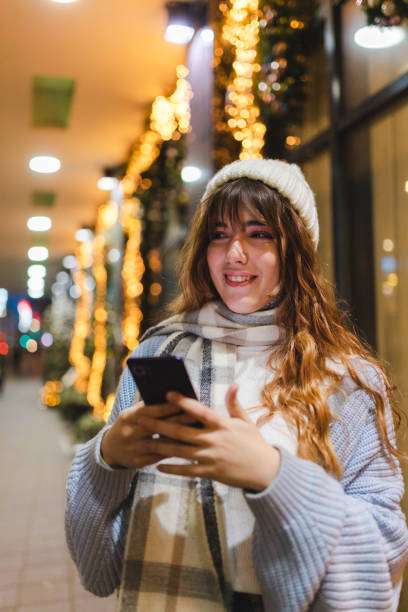 istock Smiling young woman using her phone outdoors at night 1457168865