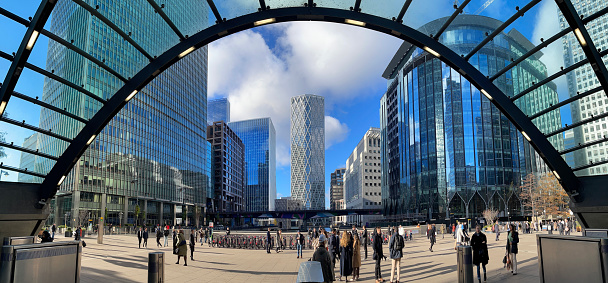 London, England, UK - November 22, 2022: Panoramic view of the modern buildings and people waiting in front of the Underground Station in Canary Wharf