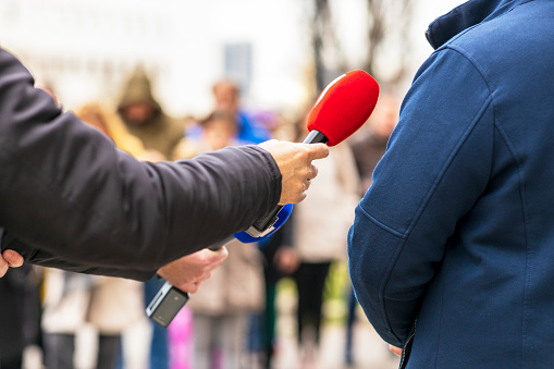 Reporter making media or vox populi interview with unrecognizable male person