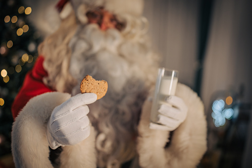 Santa Claus eating a cookie that is left for him at home.