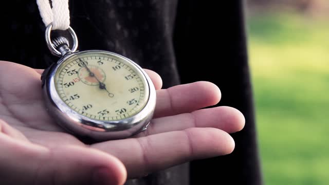 Man Hand Holding a Vintage Stopwatch Chronometer Outdoors. Close-Up.