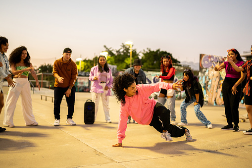 Young woman breakdancing during street party with her friends