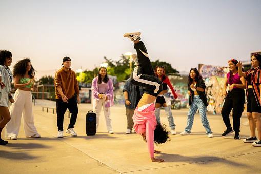 Young woman breakdancing during street party with her friends