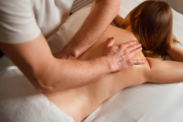 массажист делает лечебный массаж спины молодой женщине - masseur стоковые фото и изображения