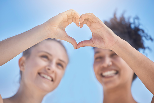 Friends, smile and heart hands on blue sky, women happy together with love and support in summer sun. Woman, girl friend and happiness, hands join to heart sign for friendship, solidarity and trust.