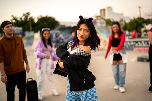 Portrait of young woman dancing hip hop during street party with her friends