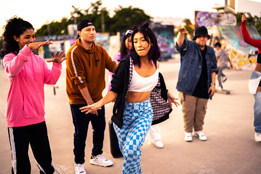 Young woman dancing hip hop during street party with her friends