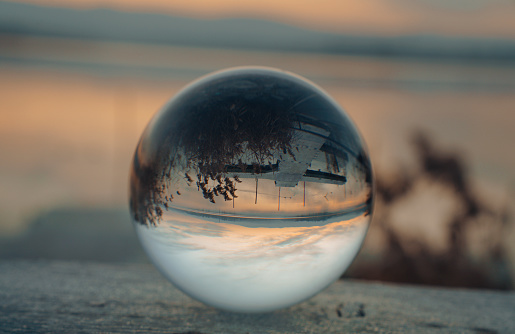 Glass orb on frozen leaves in the winter in rough nature with hills