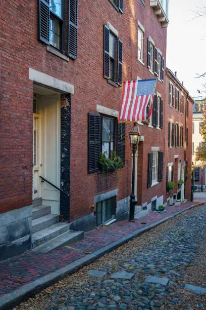Acorn Street Beacon Hill house during fall harvest with American Flag and cobblestone alley in Boston, Massachusetts.