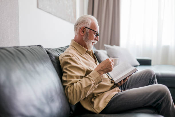 istock Senior man resting at home, drinking coffee and reading book 1457190383