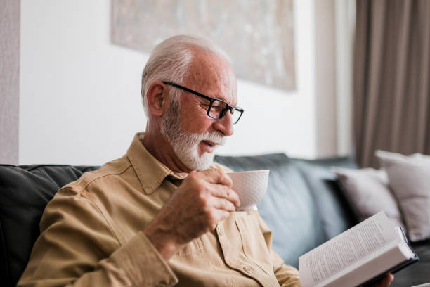istock Senior man resting at home, drinking coffee and reading book 1457190477